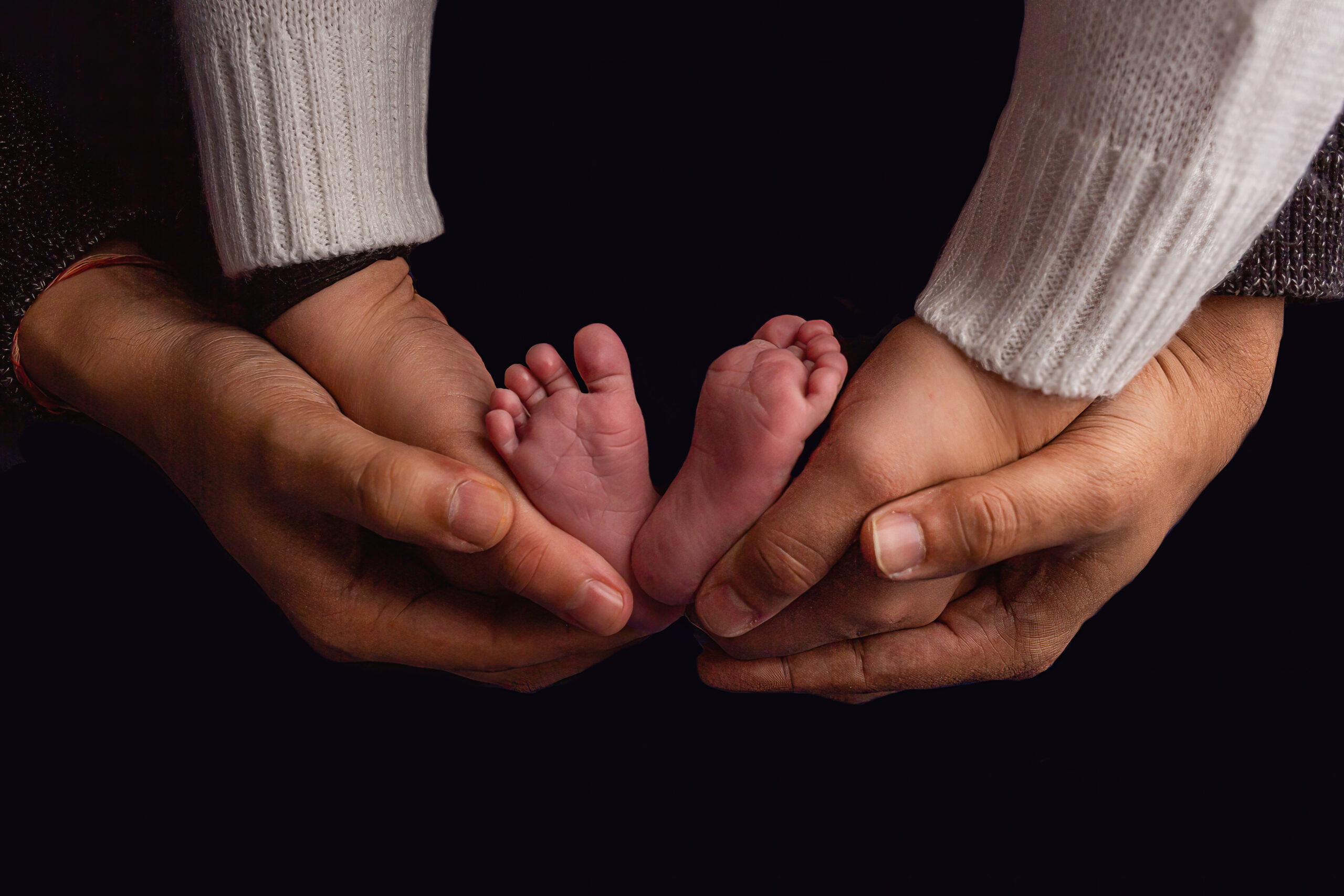 parents hands cradle newborn baby's feet during burlington newborn photography session