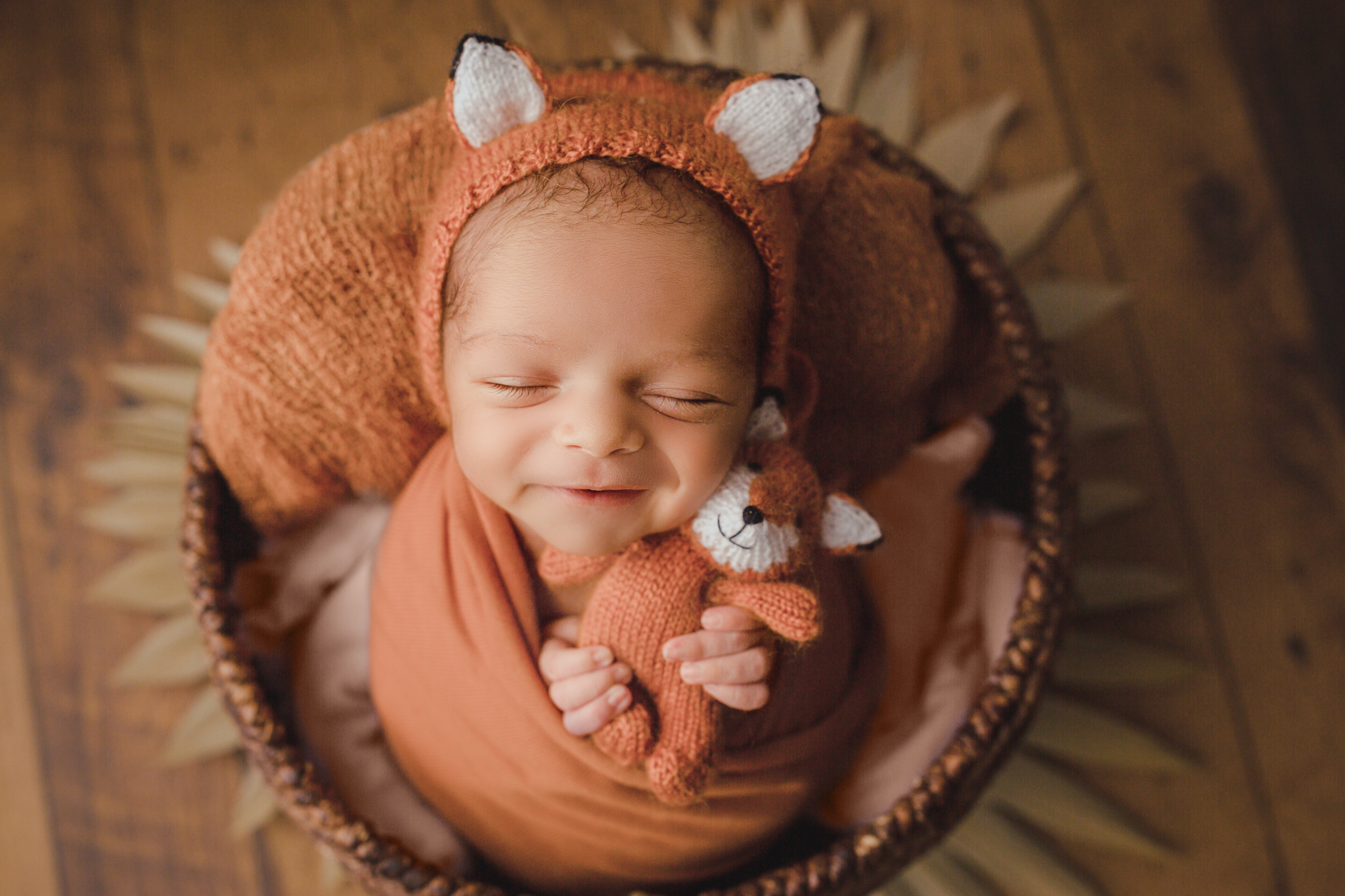 adorable baby dressed up as a fox smiles for the camera at snuggle bugz burlington photoshoot