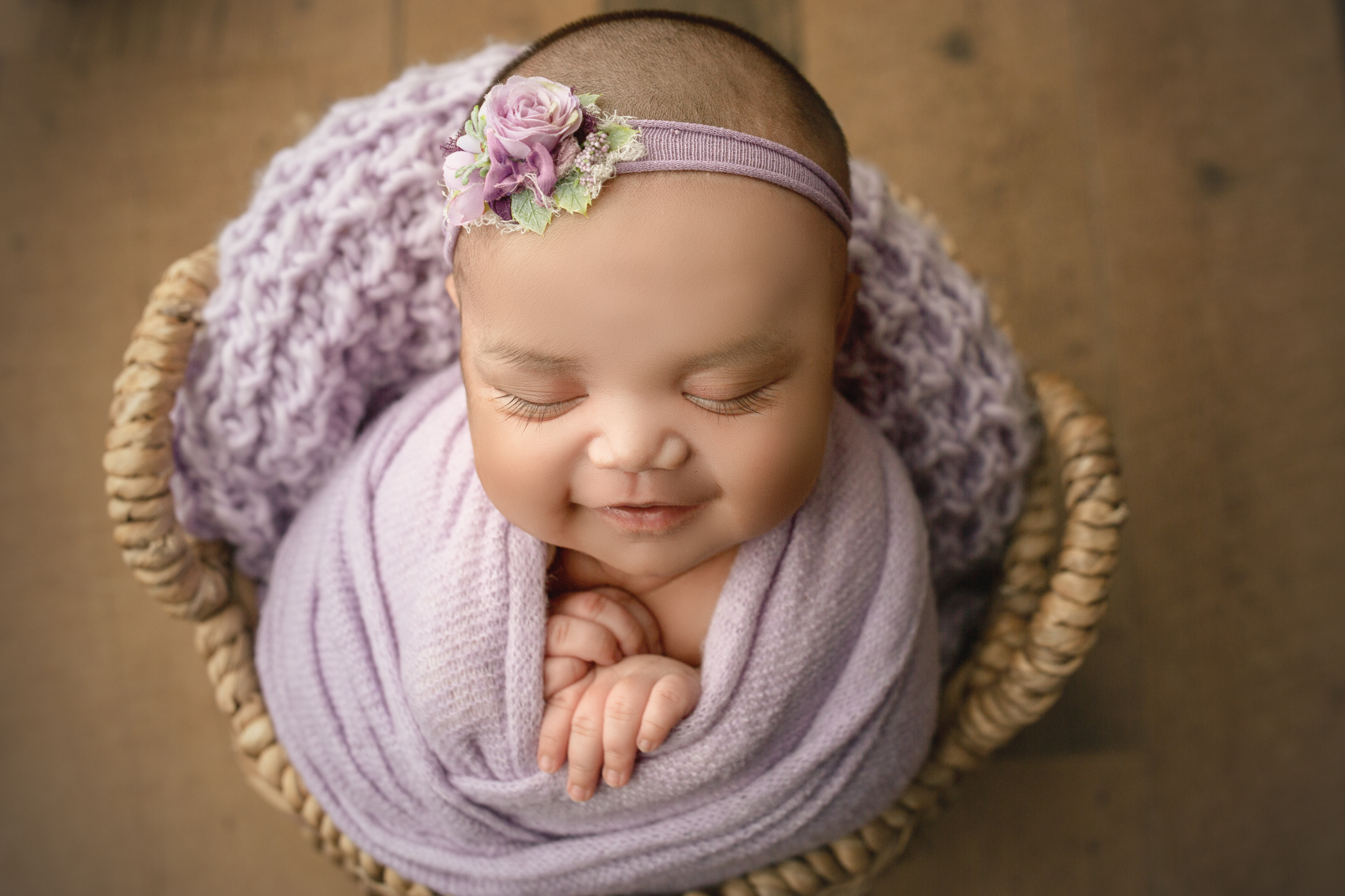 newborn baby girl wrapped in purple smiles for the camera